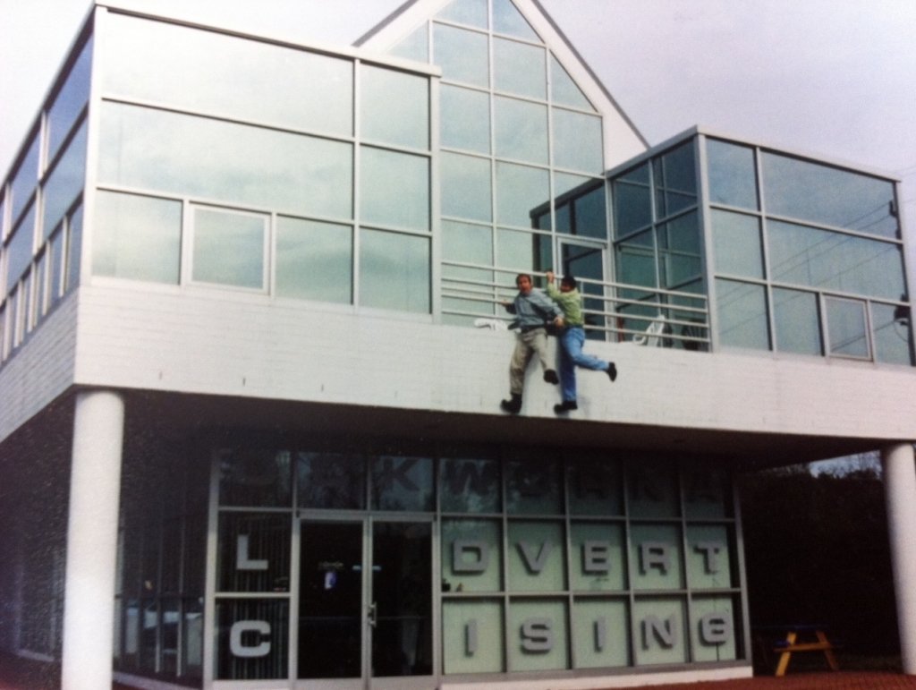 Brand Fuel owners Danny and Robert jokingly hanging from the second floor balcony railing of their original office
